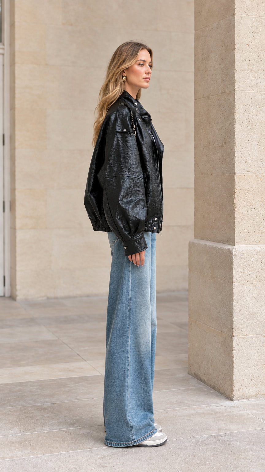 Side view of woman wearing relaxed black faux leather bomber jacket