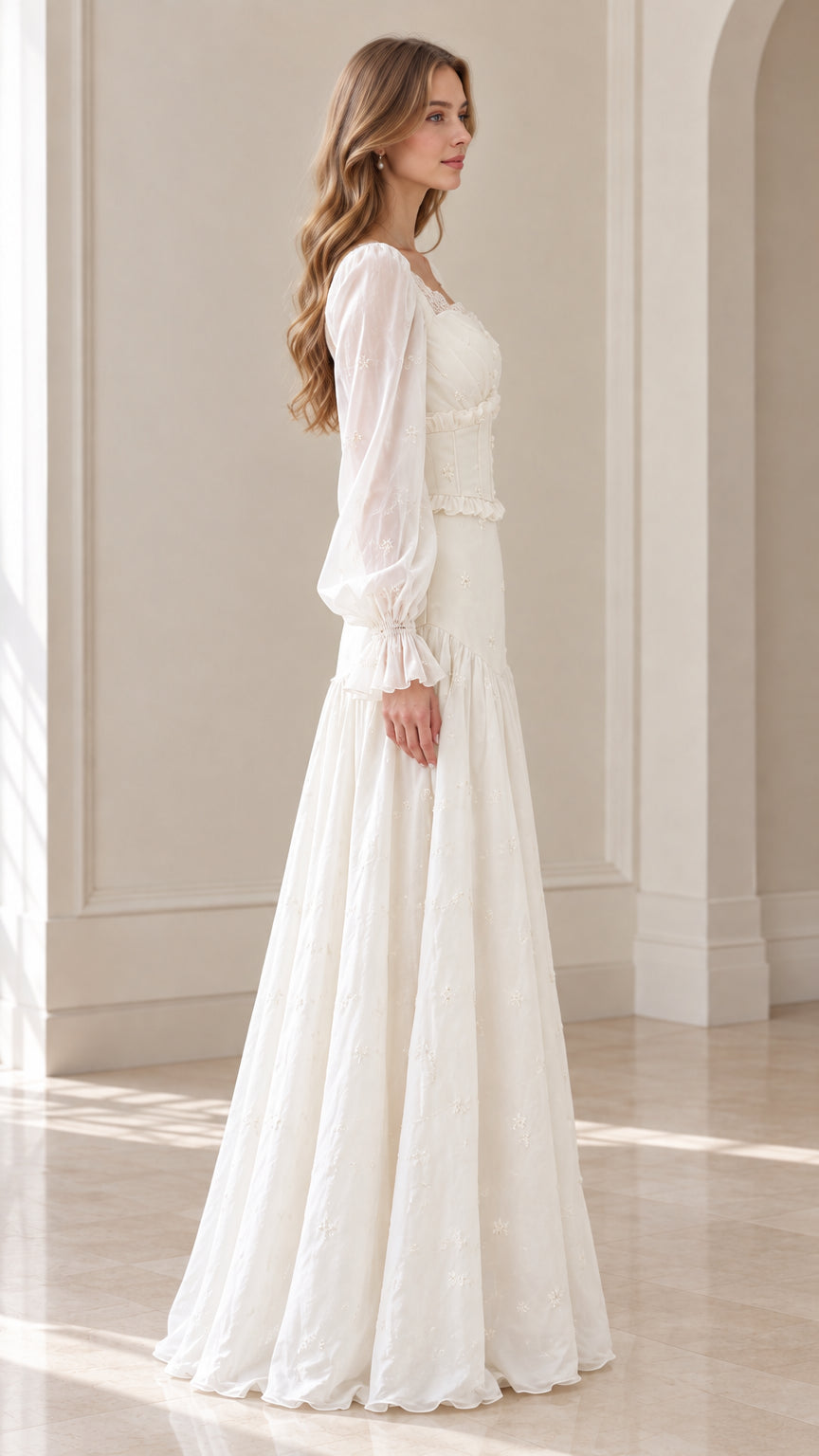 Side profile of model wearing ivory long sleeve embroidered maxi gown