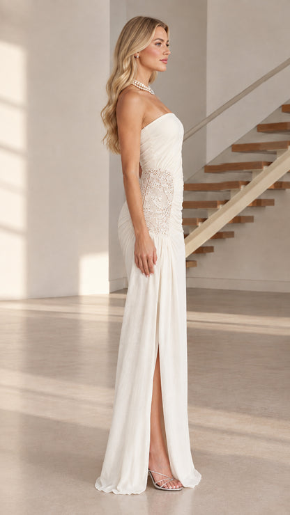 Side profile of white strapless evening gown showing leg slit and lace detail