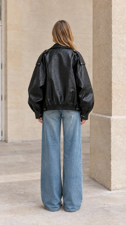 Back view of black faux leather bomber jacket showing elasticized hem and slouchy fit