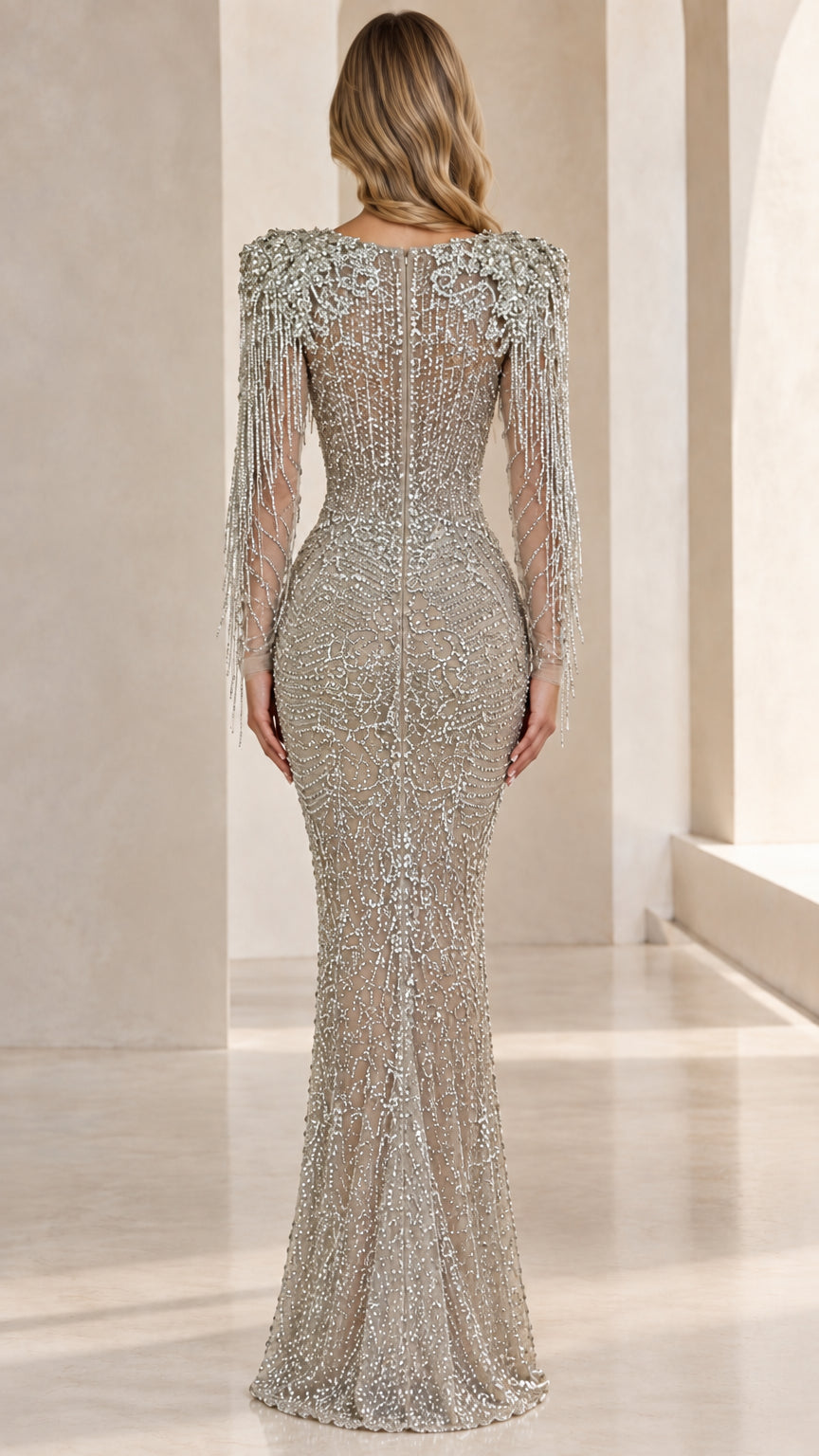 Back view of woman wearing silver illusion-back beaded gown with fringe details