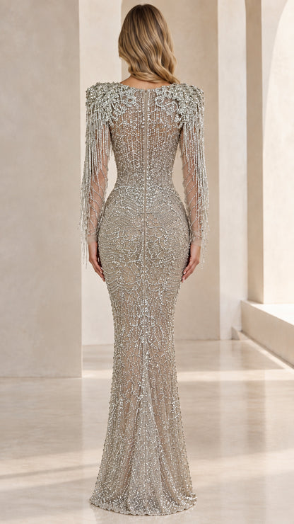 Back view of woman wearing silver illusion-back beaded gown with fringe details