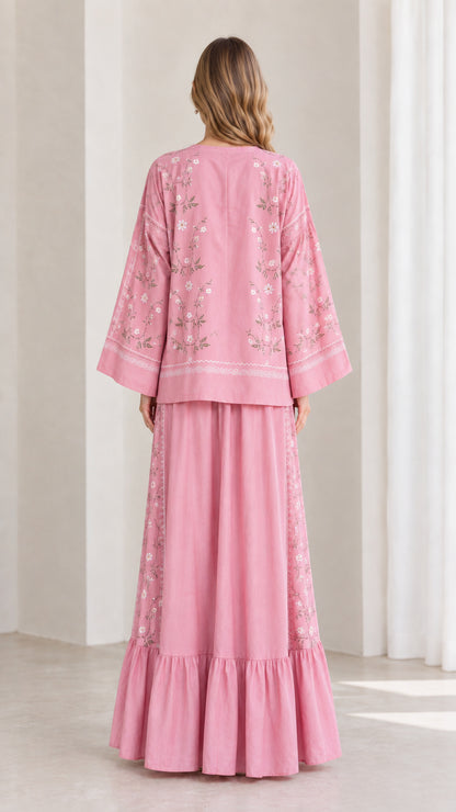 Back view of model wearing pink relaxed long sleeve top and tiered maxi skirt