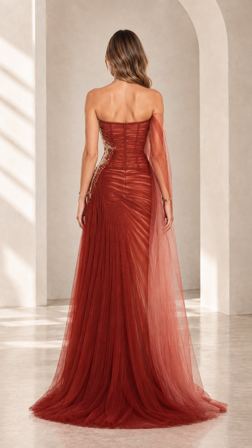 Back view of rust red strapless evening dress showing fitted corset back and trailing tulle