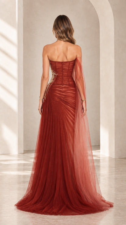 Back view of rust red strapless evening dress showing fitted corset back and trailing tulle