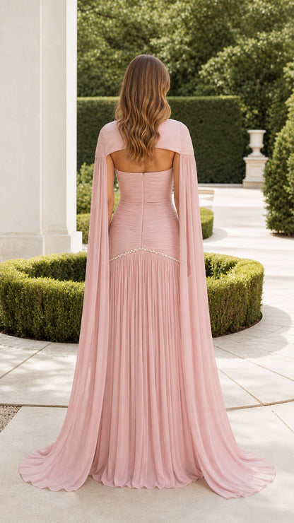 Back view of dusty pink evening gown highlighting open-back cape design and floor-sweeping train