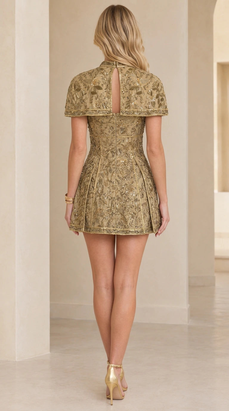 Back view of gold capelet mini dress showing keyhole opening and skirt silhouette