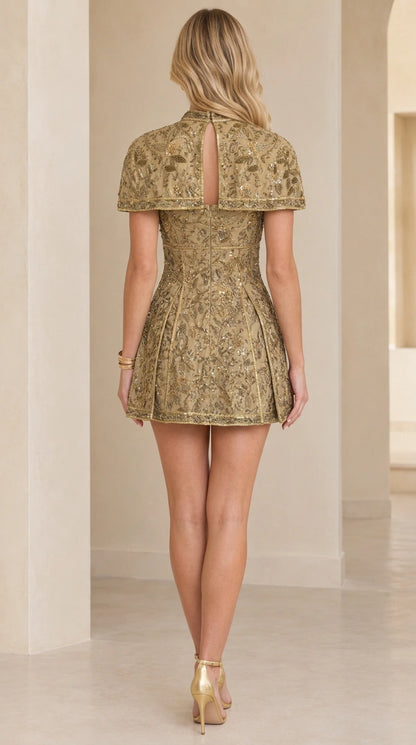 Back view of gold capelet mini dress showing keyhole opening and skirt silhouette
