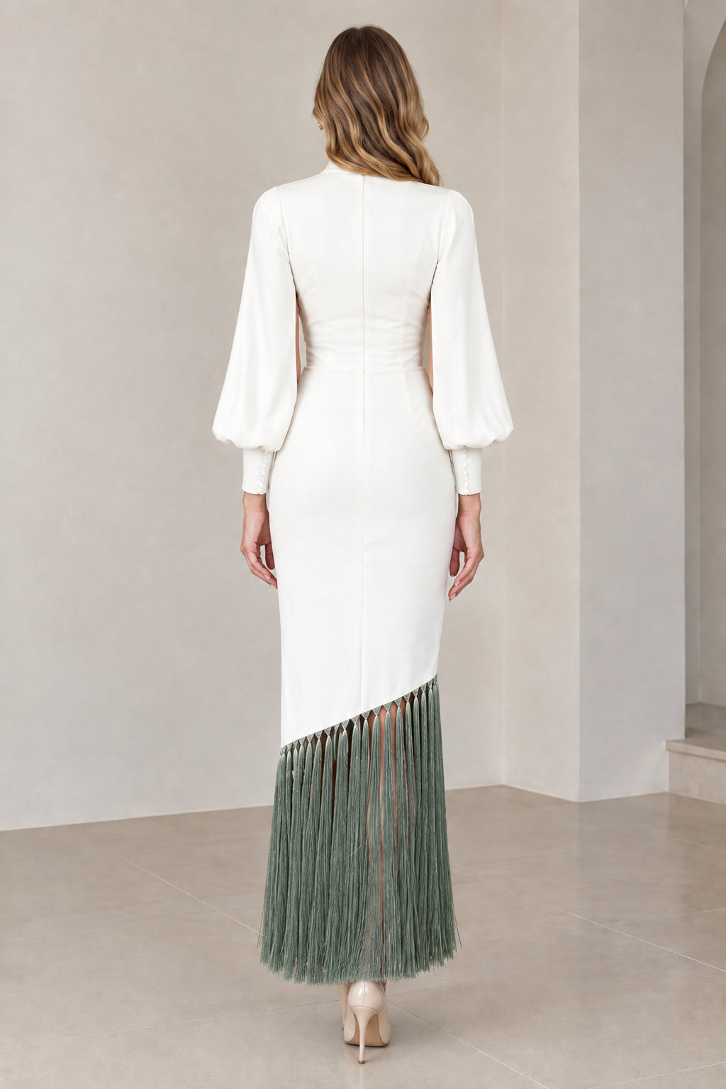 Back view of model wearing white cape sleeve dress with sage green fringe hem and back zipper