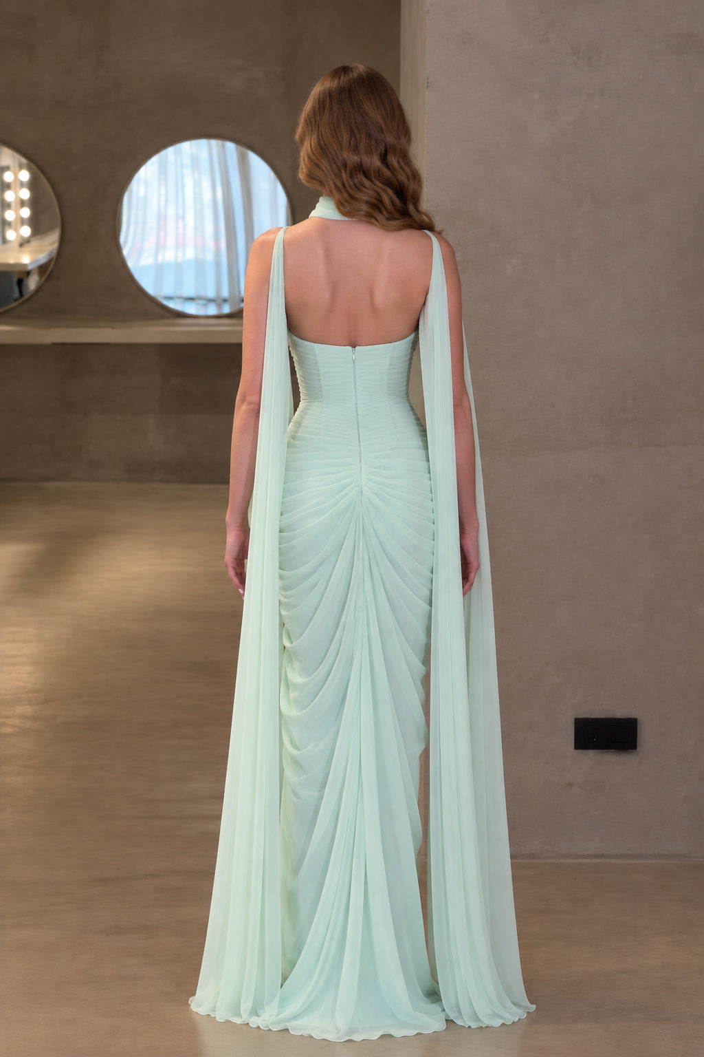 Back view of mint green evening gown highlighting low back and ruched drape