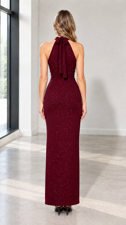 Back view of woman wearing burgundy halter maxi gown showing tie-back and hem slit