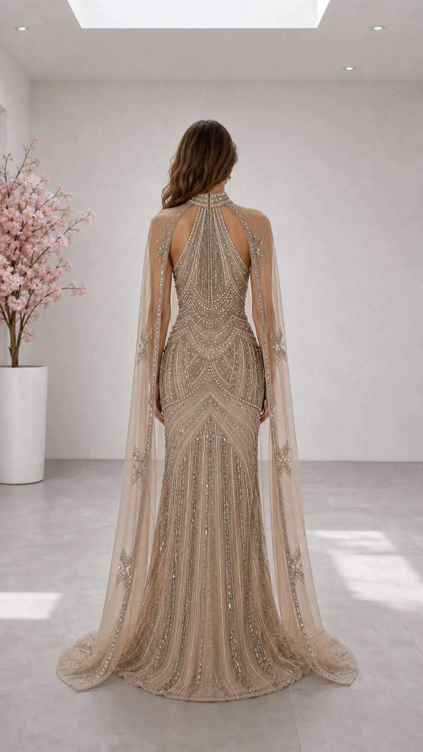 Back view of champagne halter neck gown showing cut-out back and flowing sheer cape