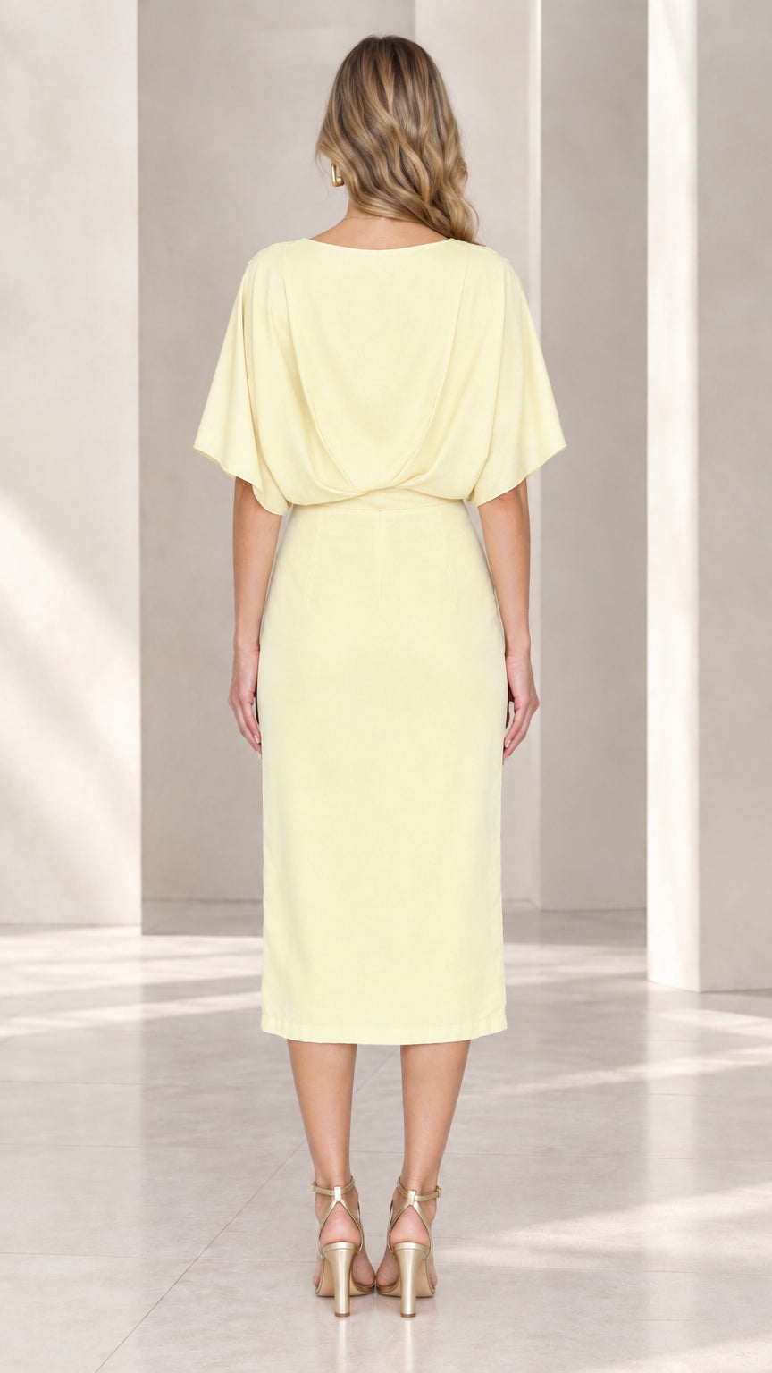 Back view of model in pale yellow midi dress showing draped back and sleek skirt