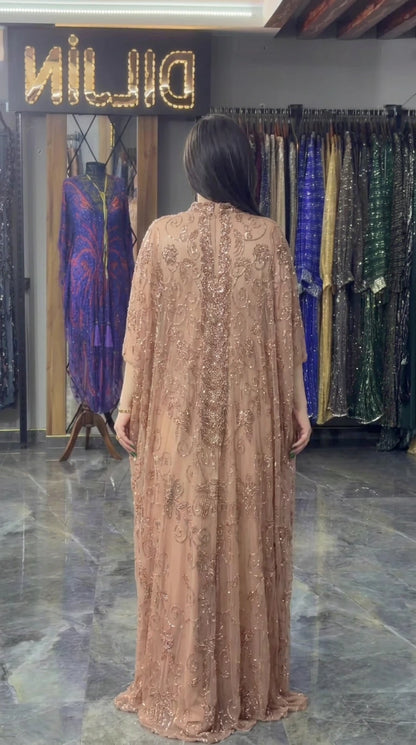 Back view of model in flowing champagne beaded formal gown