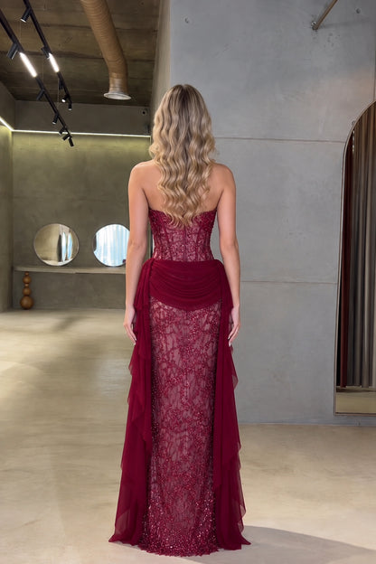 Back view of model wearing burgundy strapless corset gown with draped back train