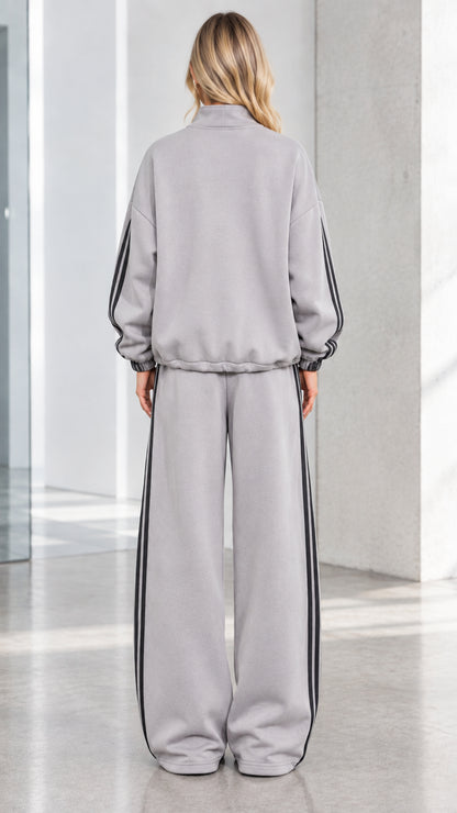 Back view of woman wearing Heather Grey relaxed track jacket and wide-leg pants