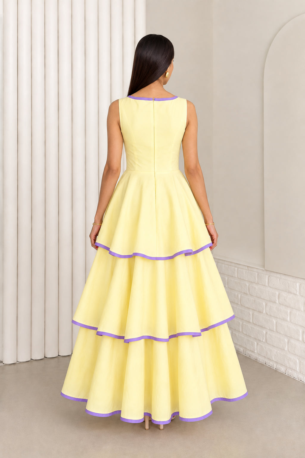 Back view of model in pastel yellow sleeveless tiered maxi dress