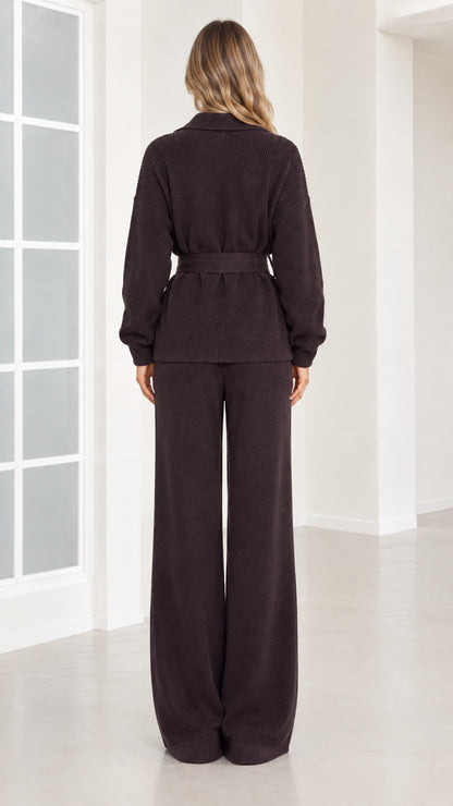 Back view of woman wearing dark brown ribbed knit belted top and wide-leg trousers
