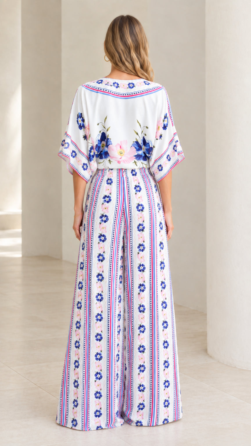 Back view of model showing flowy fit of white floral tie-front top and palazzo pants