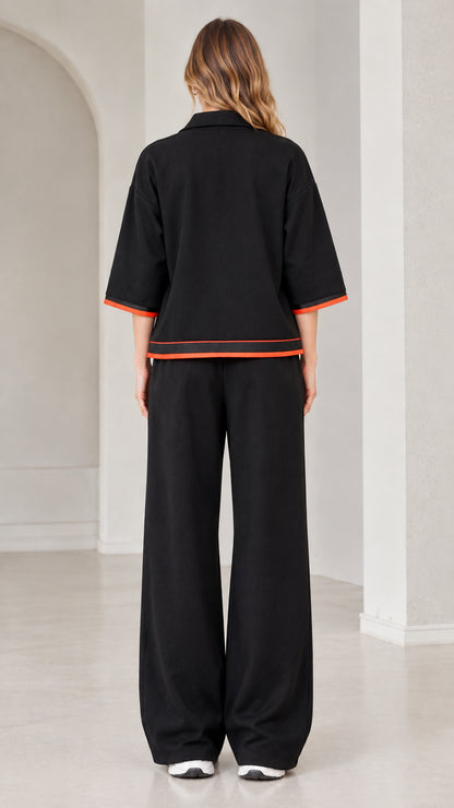 Back view of woman wearing black relaxed fit tracksuit with contrast cuff and hem accents