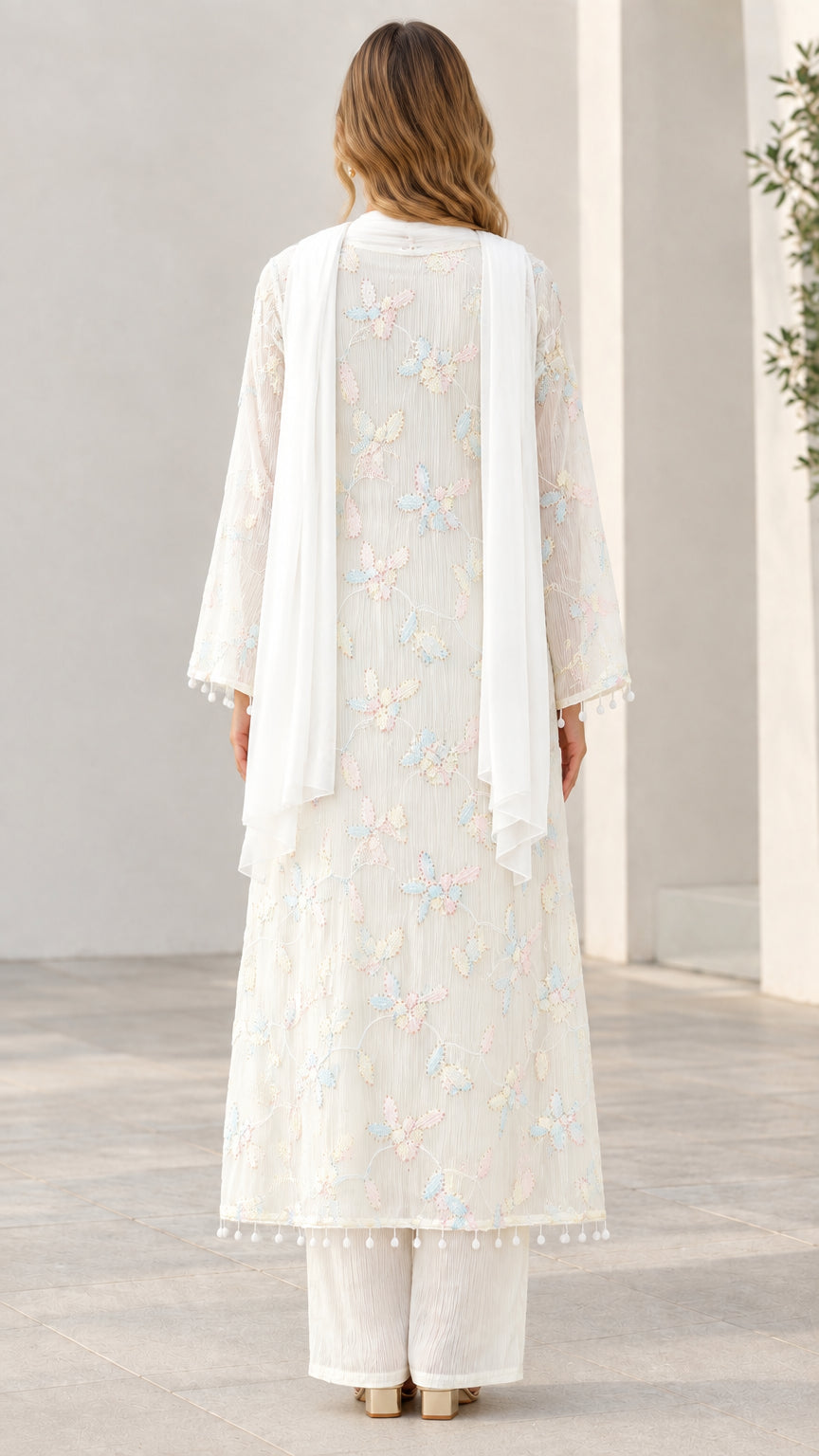 Back view of model in white embroidered kurta set with flowing scarf
