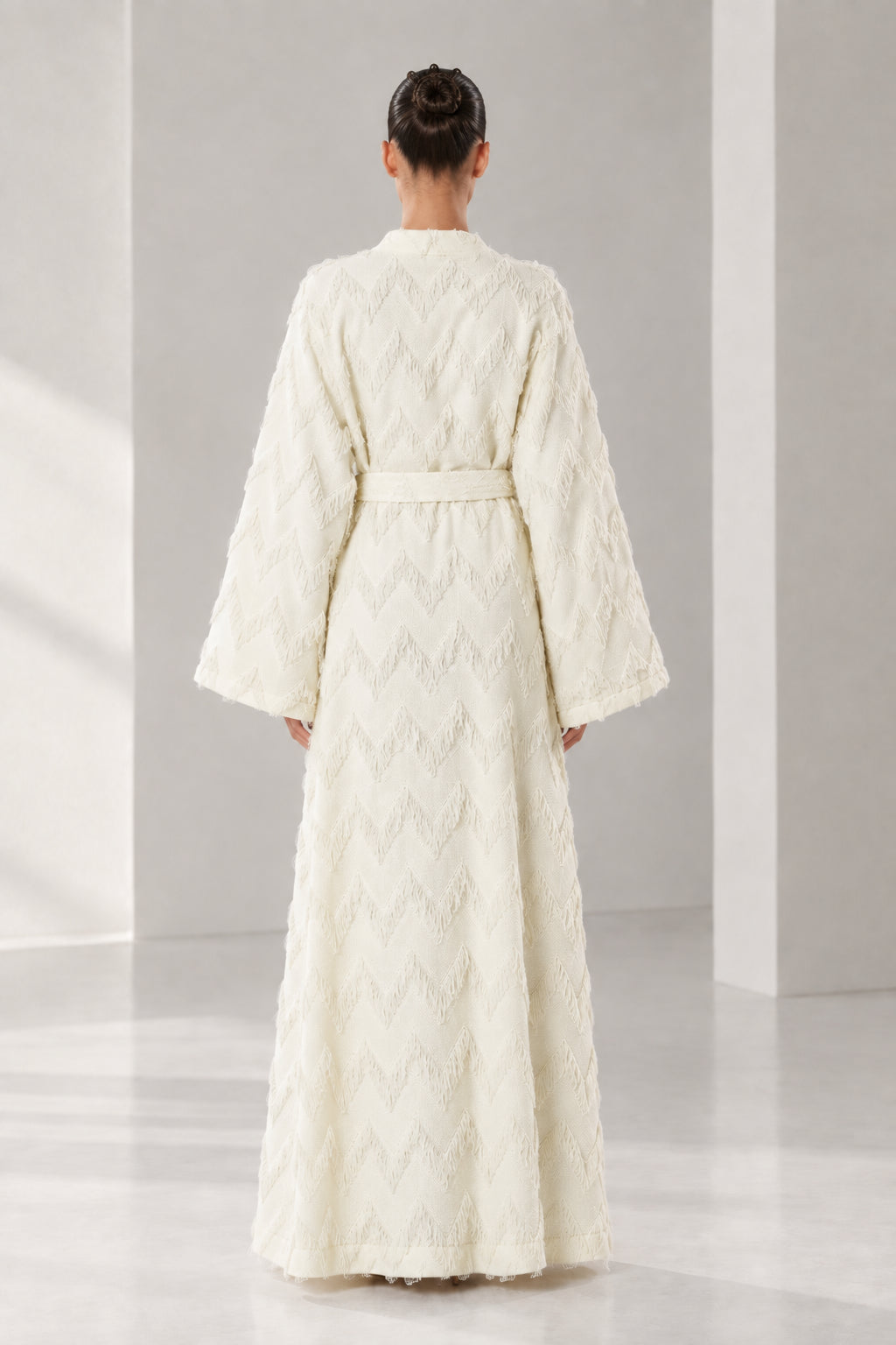 Back view of woman wearing cream belted maxi robe with textured chevron weave