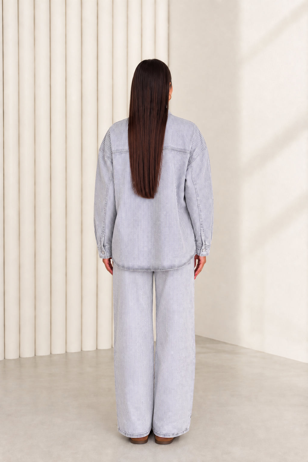 Back view of model in light blue striped denim shacket and wide leg jeans