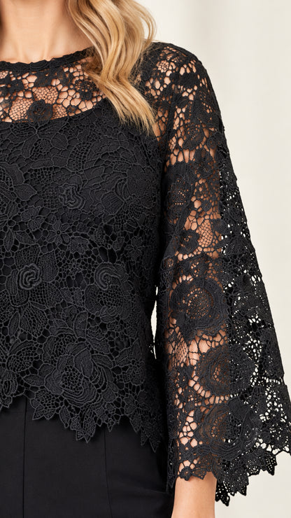 Close-up detail of black floral lace texture, scalloped hem, and flared sleeves