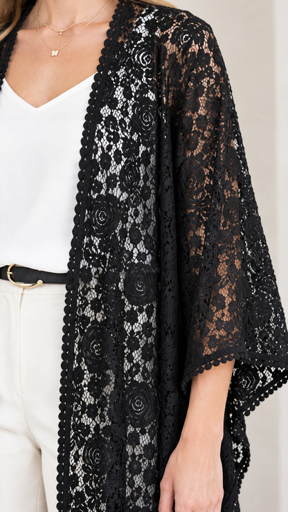 Close-up detail of sheer floral lace fabric and scalloped border on black duster