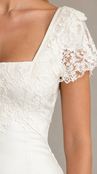 Close-up detail of white floral lace sleeve and neckline embroidery