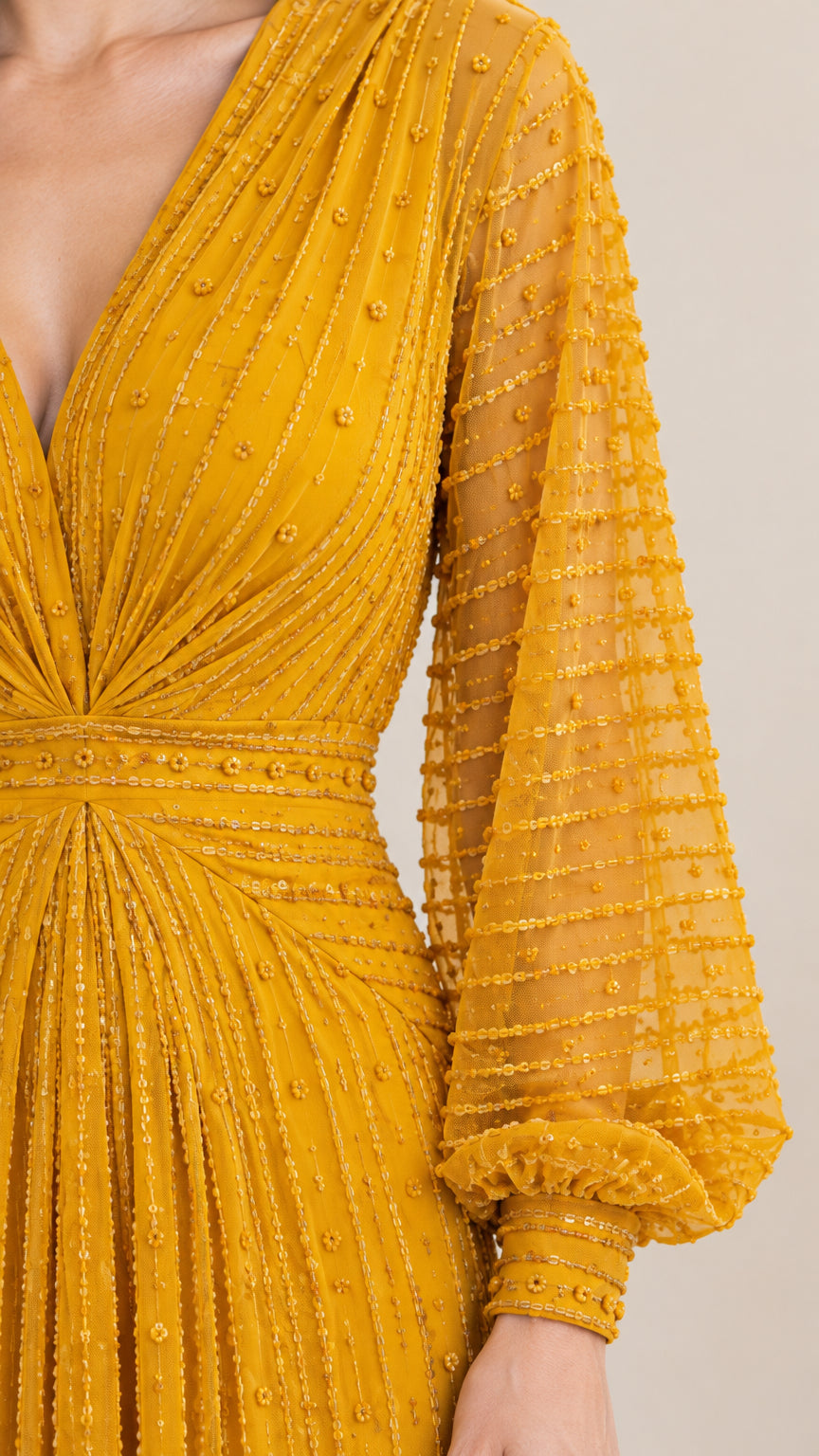 Close-up detail of textured fabric, gathered V-neckline, and bishop sleeve cuff