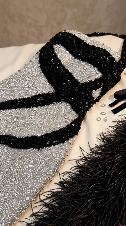 Close-up detail of intricate silver sequins and textured black contour ribbon embellishment