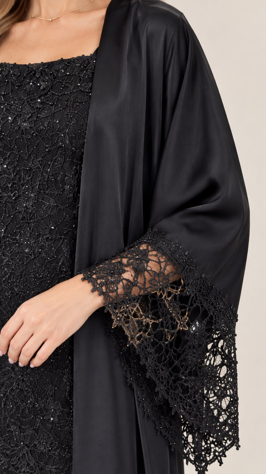 Close-up of the square neckline and detailed scalloped lace cuffs on the black formal set