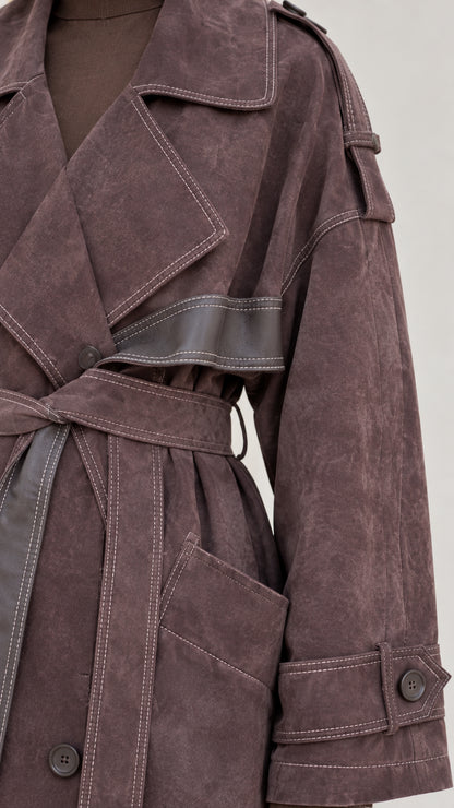 Close-up detail of contrast topstitching, wide lapel, and cuff strap on brown coat