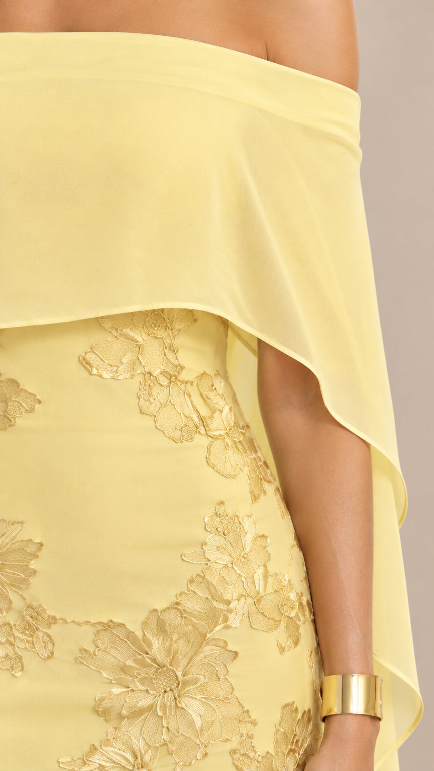 Close-up detail of textured floral embroidery and chiffon capelet on yellow gown