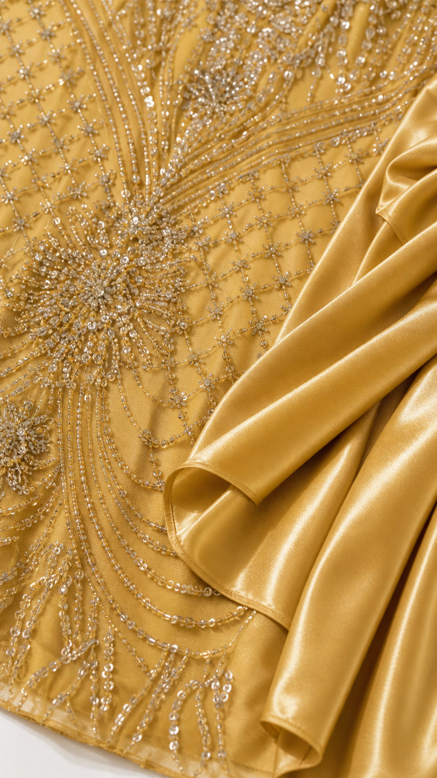 Close-up of gold sequin and bead embroidery alongside glossy satin drapery