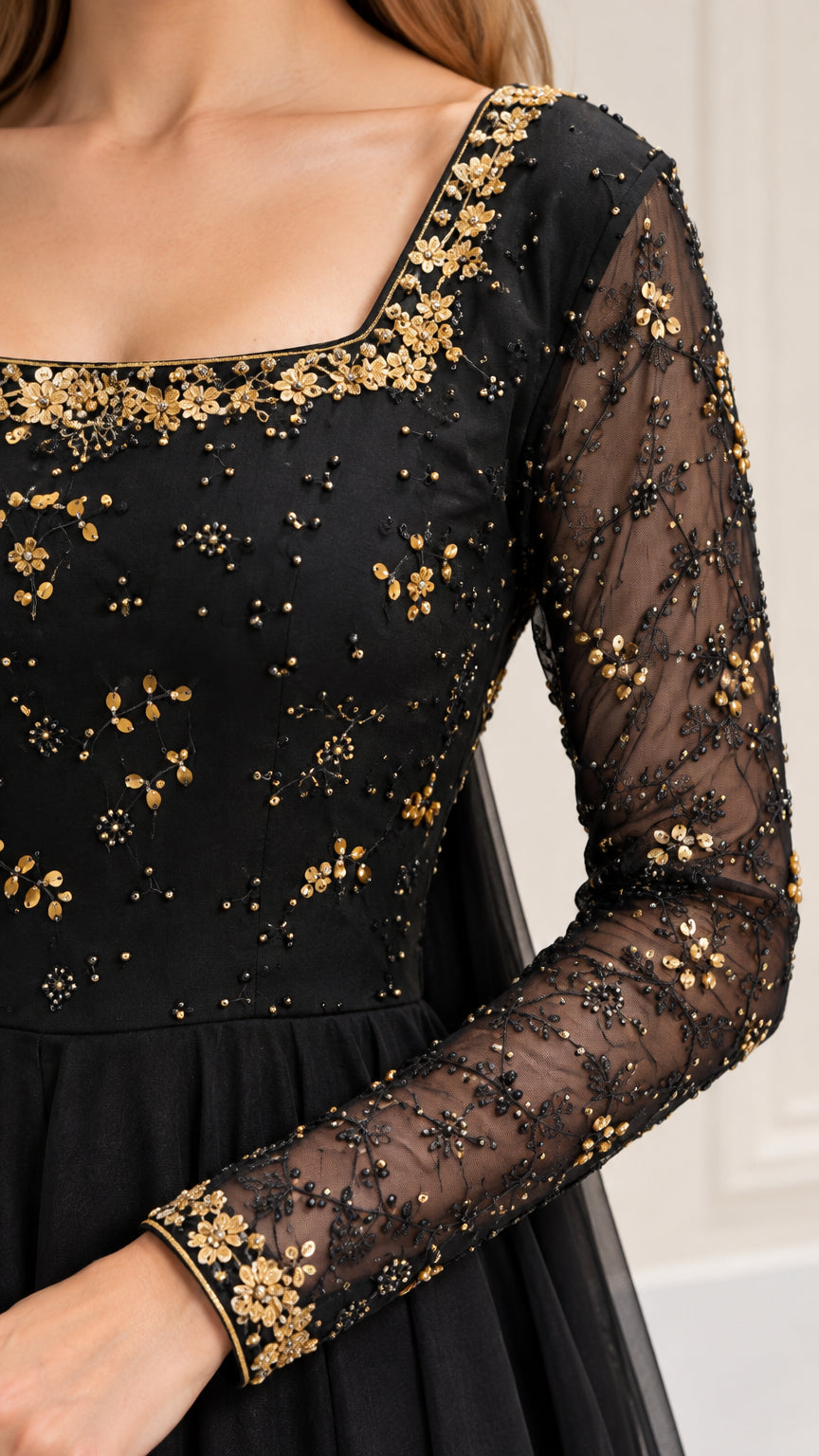 Close-up of gold-tone floral embroidery and beading on black sheer bodice and sleeve