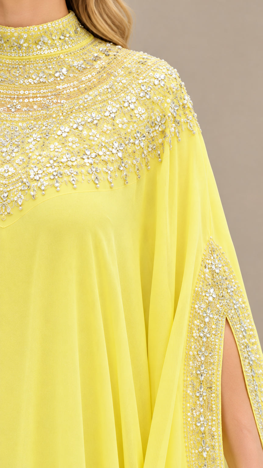 Close-up of sparkling beadwork and crystal embellishments on yellow kaftan neckline and sleeve