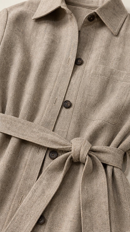 Close-up detail of textured fabric, buttons, and self-tie waist belt on oatmeal jacket