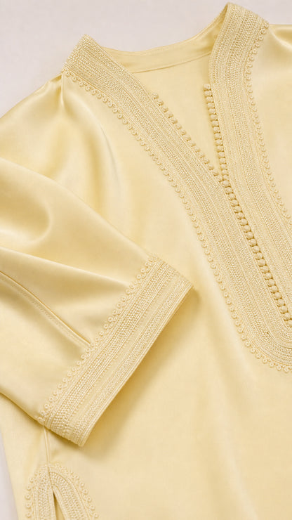 Close-up detail of textured embroidery on neckline and cuff of pastel yellow tunic