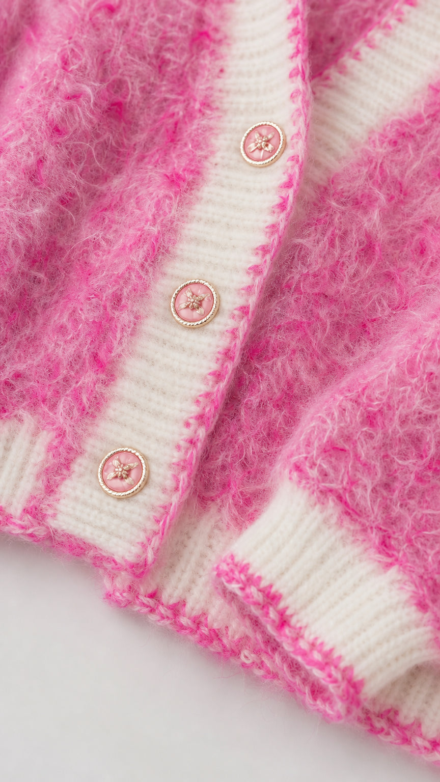 Close-up detail of pink fuzzy knit texture with contrast white trim and decorative button