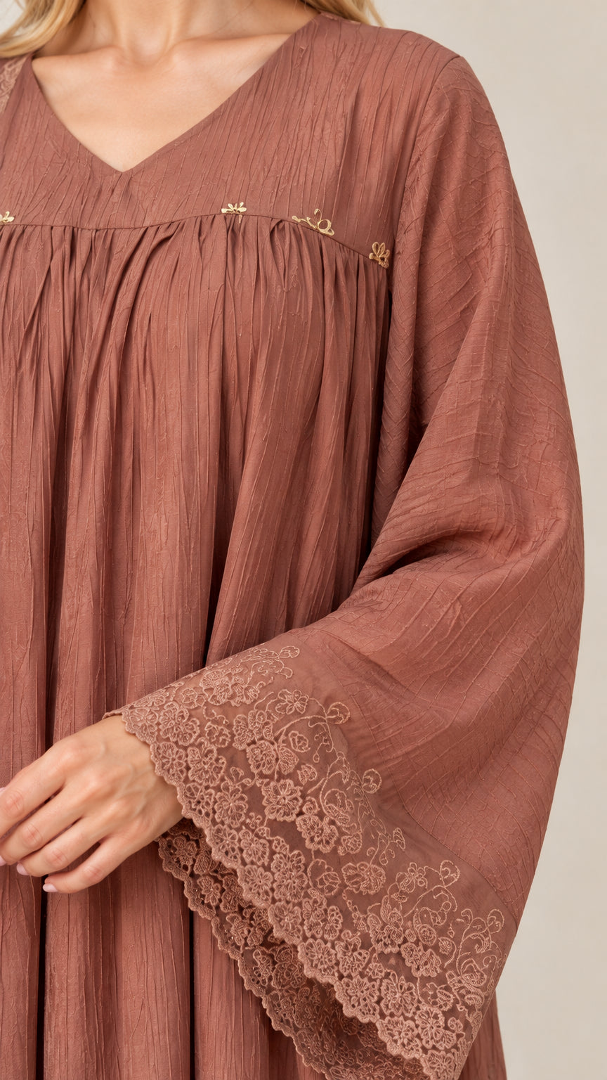 Close-up detail of dusty rose pleated V-neck tunic, crinkle texture, and floral lace cuff