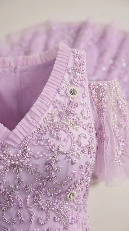 Close-up detail of lavender gown showing intricate beading, pleating, and cold-shoulder sleeve