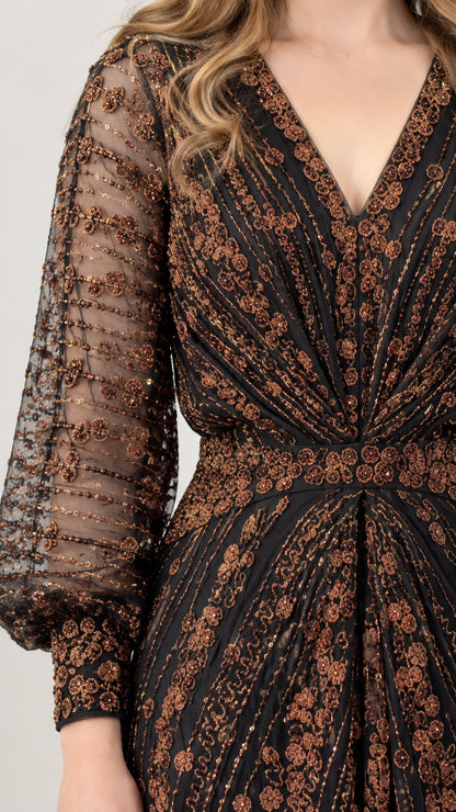 Close-up detail of sheer lantern sleeve with intricate bronze sequin pattern and button cuff