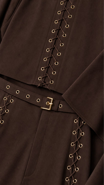 Close-up detail of metal eyelet grommets, lace-up cord accents, and belted waistband