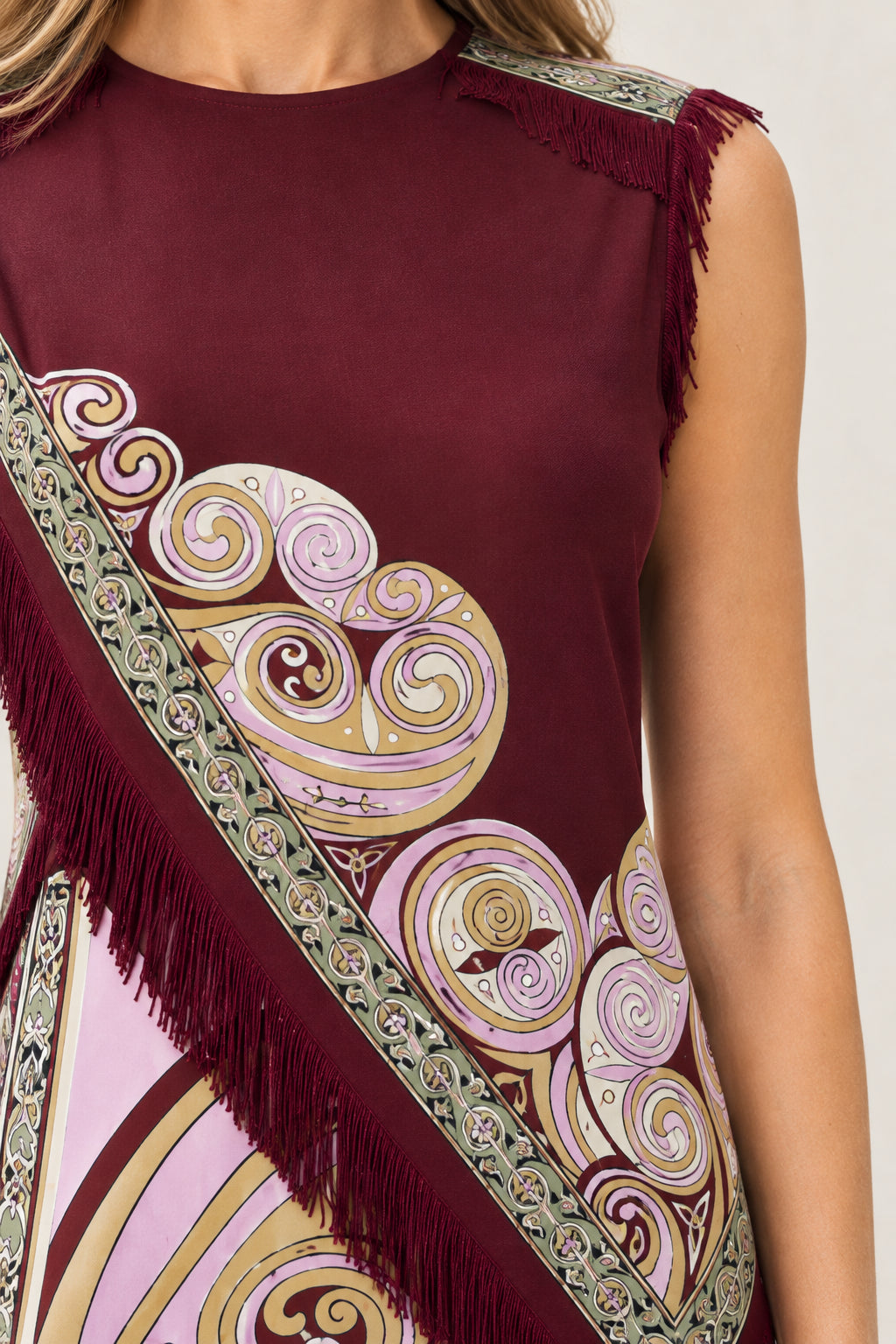 Close-up detail of baroque swirl pattern and fringe trim on Burgundy mini dress