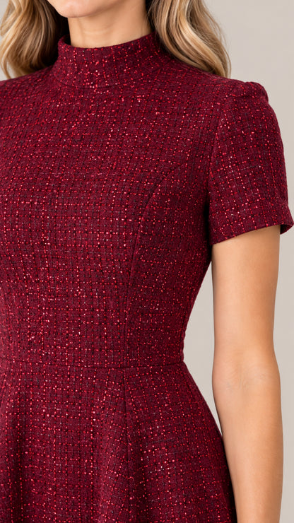 Close-up detail of burgundy tweed fabric with woven texture and mock neckline