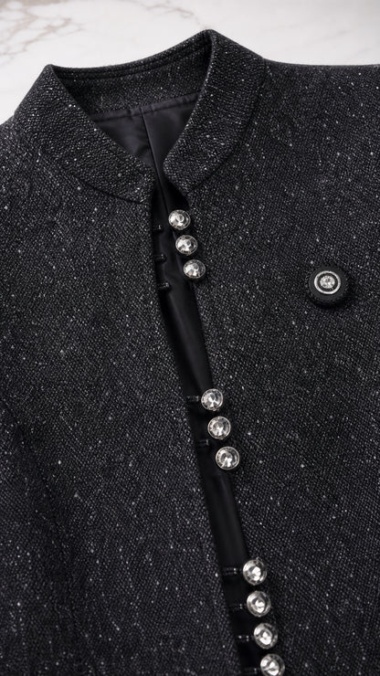 Close up of textured black tweed jacket with crystal button details and stand collar