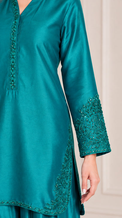 Close-up of intricate embroidery on neckline, cuffs, and hem of teal satin tunic