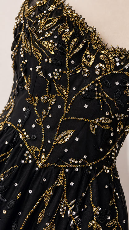 Close-up detail of botanical sequin and bead embroidery on black mesh fabric